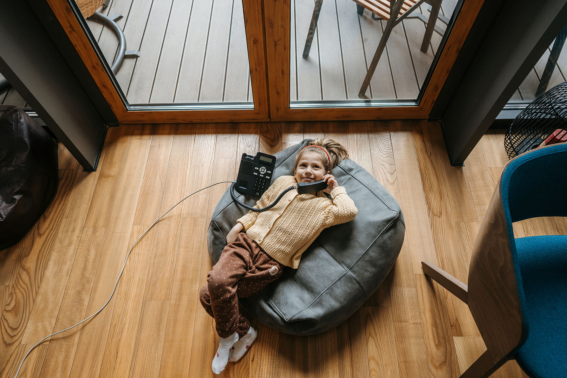 young girl talking on a home telephone while reclining in a bean bag chair